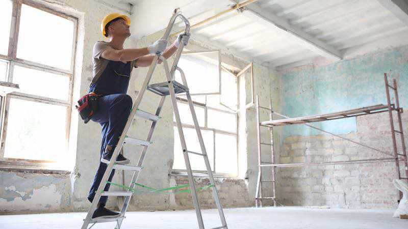 Ouvrier avec une échelle dans un bâtiment