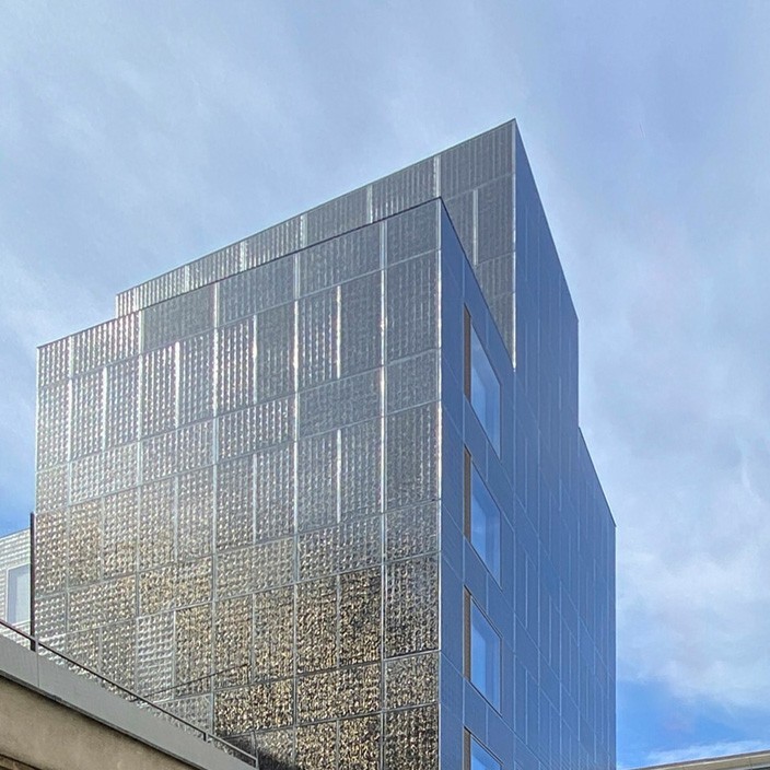 Un reflet doré unique en son genre enveloppe la façade solaire du nouveau bâtiment de l' OEE à Bâle.