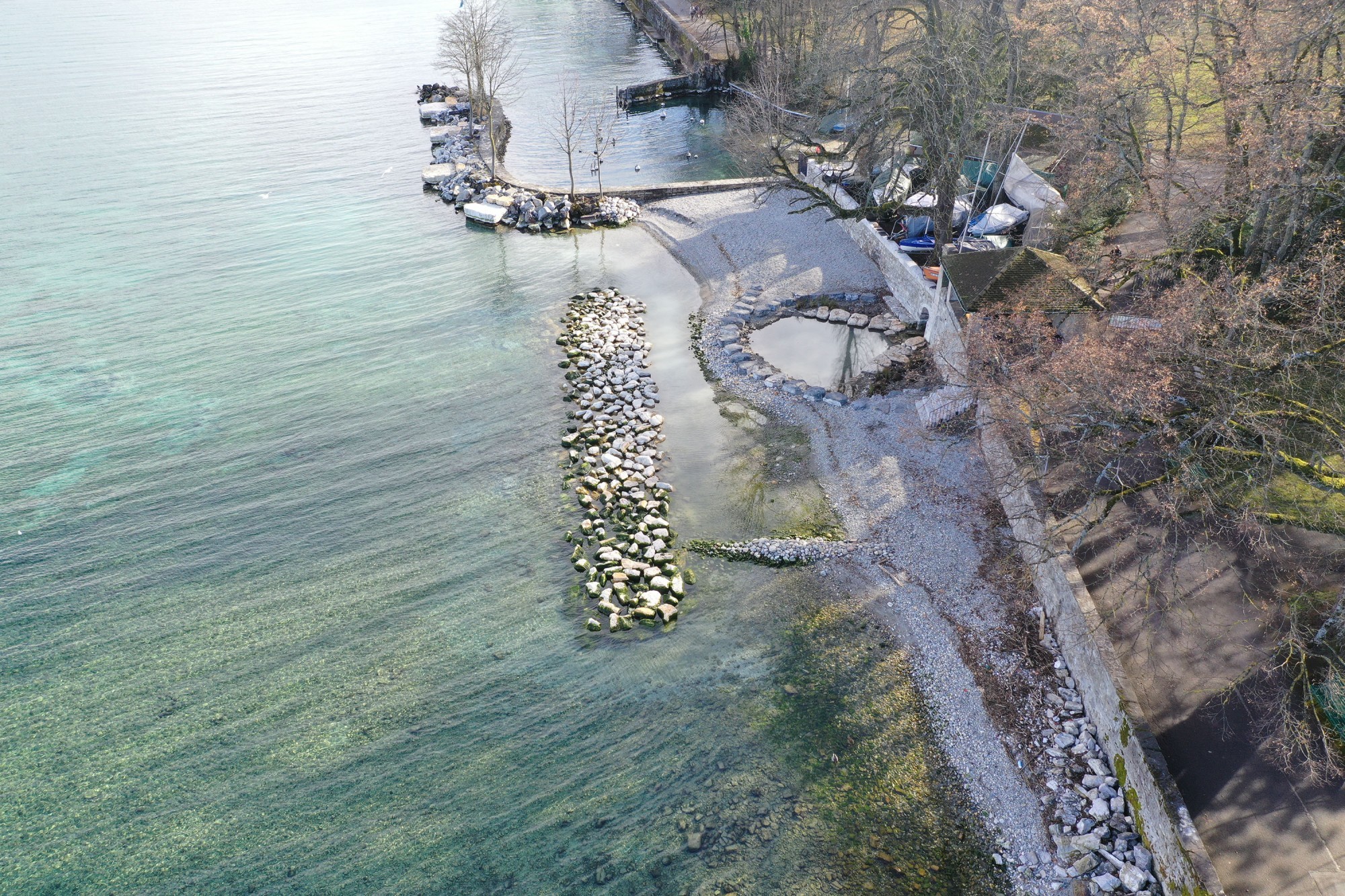 130 m de rive et digue adjacente au port ont été réaménagés en plage de galets et une digue sous-lacustre brise l'énergie des vagues du site très exposé à la bise.