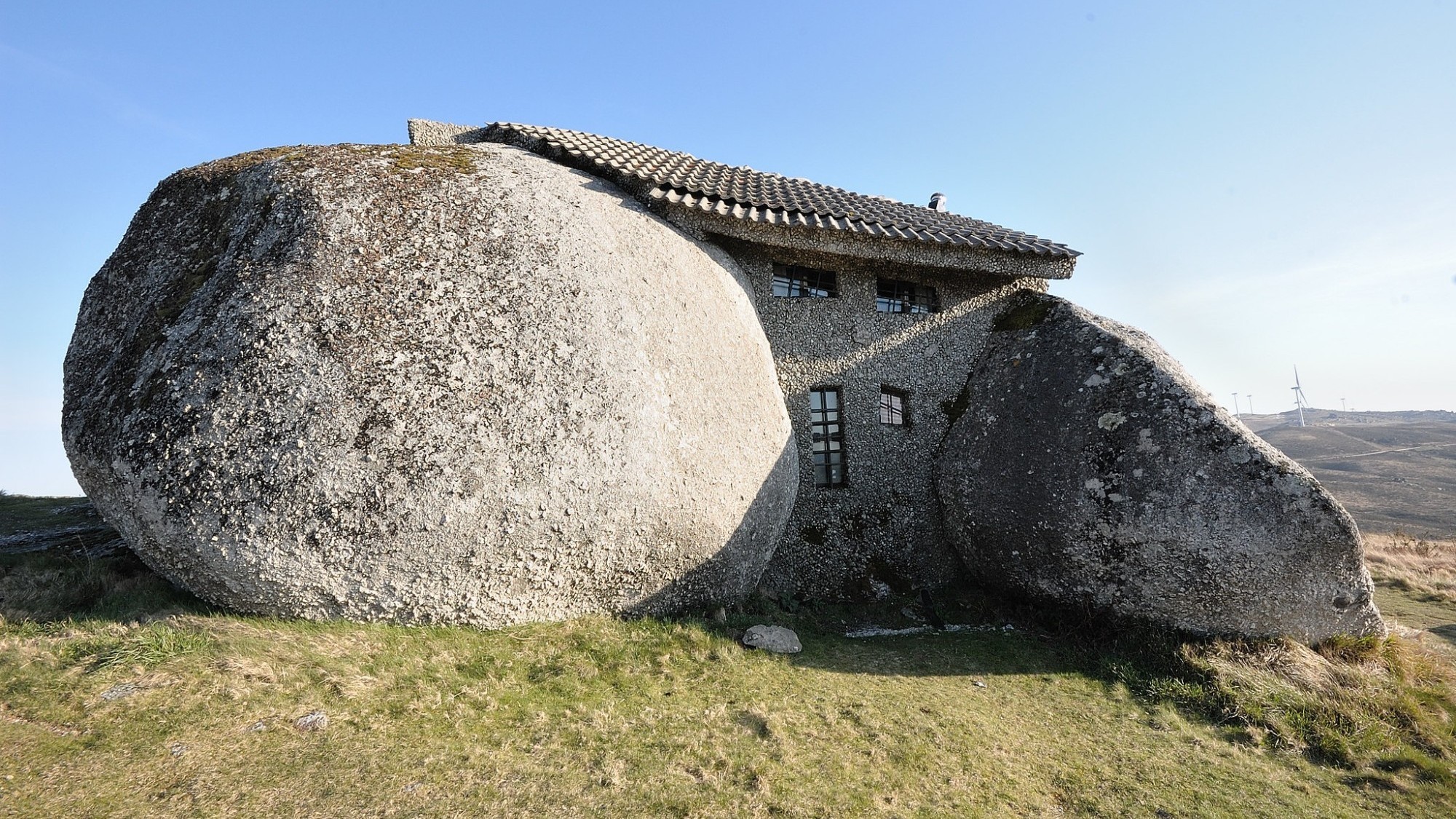 La Casa do Penedo dans la commune de Fafe au Portugal a été construite à partir de quatre énormes blocs de roche. Elle se trouve à proximité d'éoliennes.