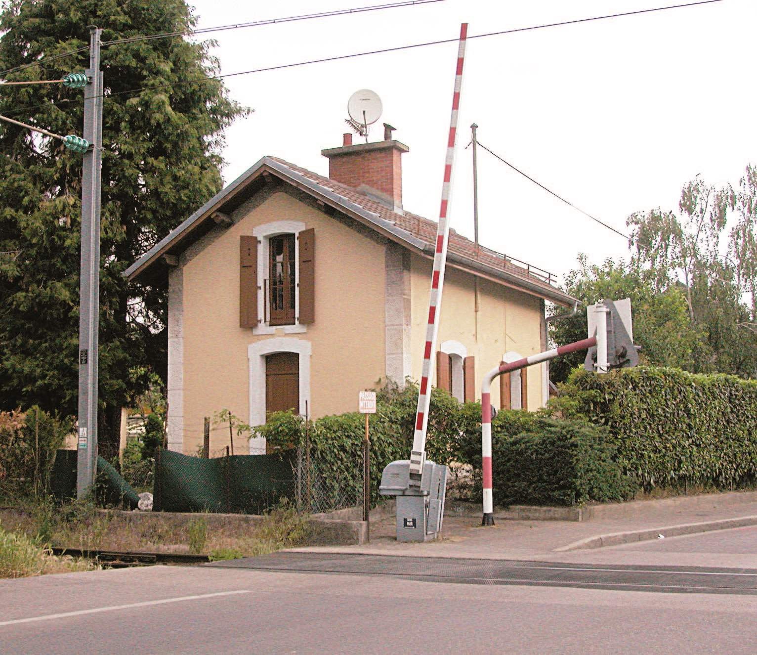 La maison de garde-barrière type de la Compagnie des chemins de fer de Paris à Lyon et à la Méditerranée (PLM) est construite à proximité immédiate d'un passage à niveau perpendiculairement aux voies.