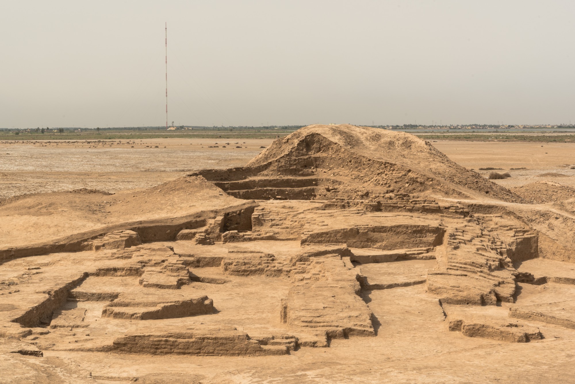 Le temple dédié au dieu Ningursu, datant d'environ 2'100 avant J.-C. : une vue des fouilles menées par l'équipe du British Museum et, en arrière-plan, un terril datant du XIXe siècle qui surplombe les vestiges archéologiques.