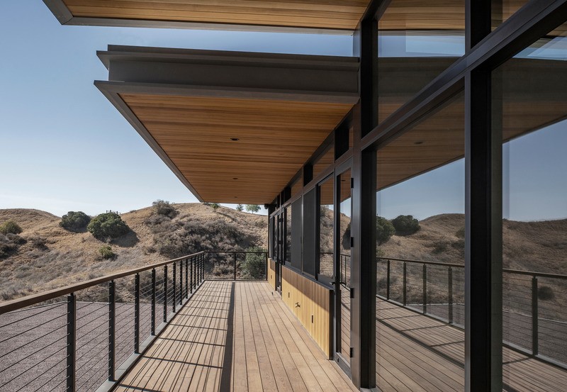 Au niveau supérieur, un balcon linéaire et une terrasse dominent le désert aride.