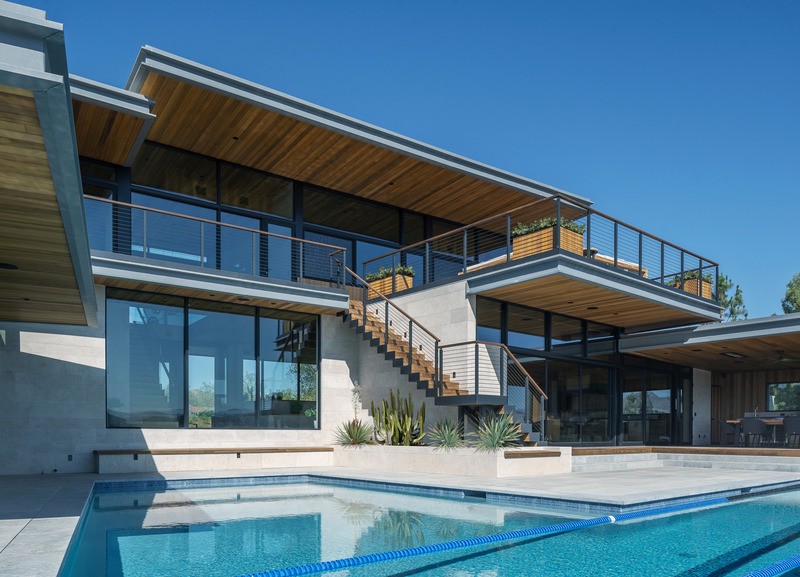 Le niveau inférieur, qui abrite une salle de sport, une buanderie, une suite pour les invités et une terrasse pour la piscine, se prolonge dans le flanc de la colline, offrant une vue panoramique dégagée