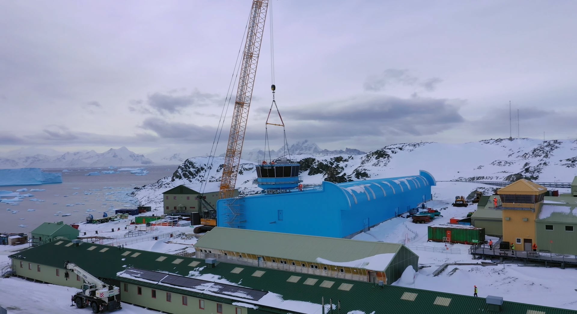 Levage du sommet de la station par une grue sur le nouveau bâtiment de recherche. Grâce à un revêtement métallique bleu, le nouveau bâtiment est protégé des intempéries juste avant l'arrivée de l'hiver antarctique.