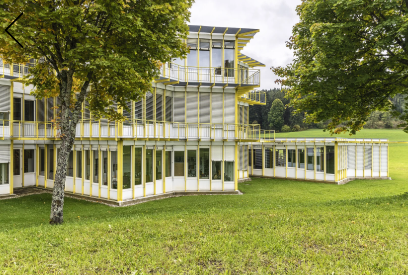 La forme de base du centre de perfectionnement de Tramelan se compose de deux carrés superposés en étoile. La structure se pose comme un tapis sur les douces collines du Jura bernois. Des couleurs et des matériaux typiques de l’époque accompagnent la succ