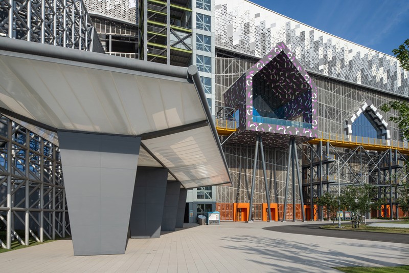 Place d’accueil du Musée des déchets, où des volumes de « mini-ville » sont intégrés à la façade industrielle.