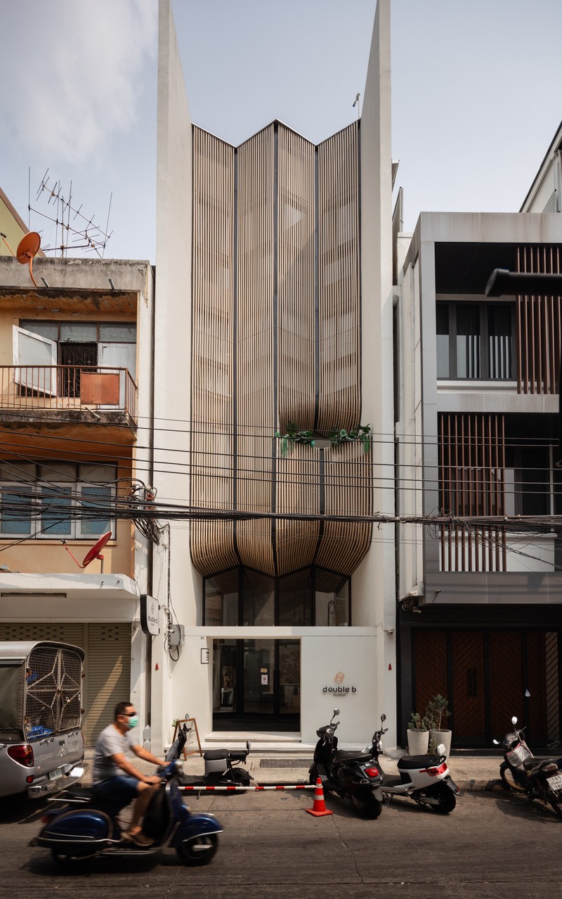MA Design Studio a achevé la construction du Double B Hostel à Bangkok en utilisant des façades en bois fluides qui allient l'artisanat local au design contemporain.