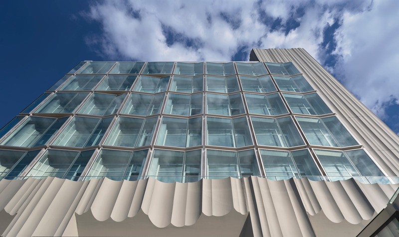 La façade en verre de Quartz Plaza utilise des panneaux inclinés et des revêtements brillants pour créer des reflets inspirés des cristaux et des prismes.
