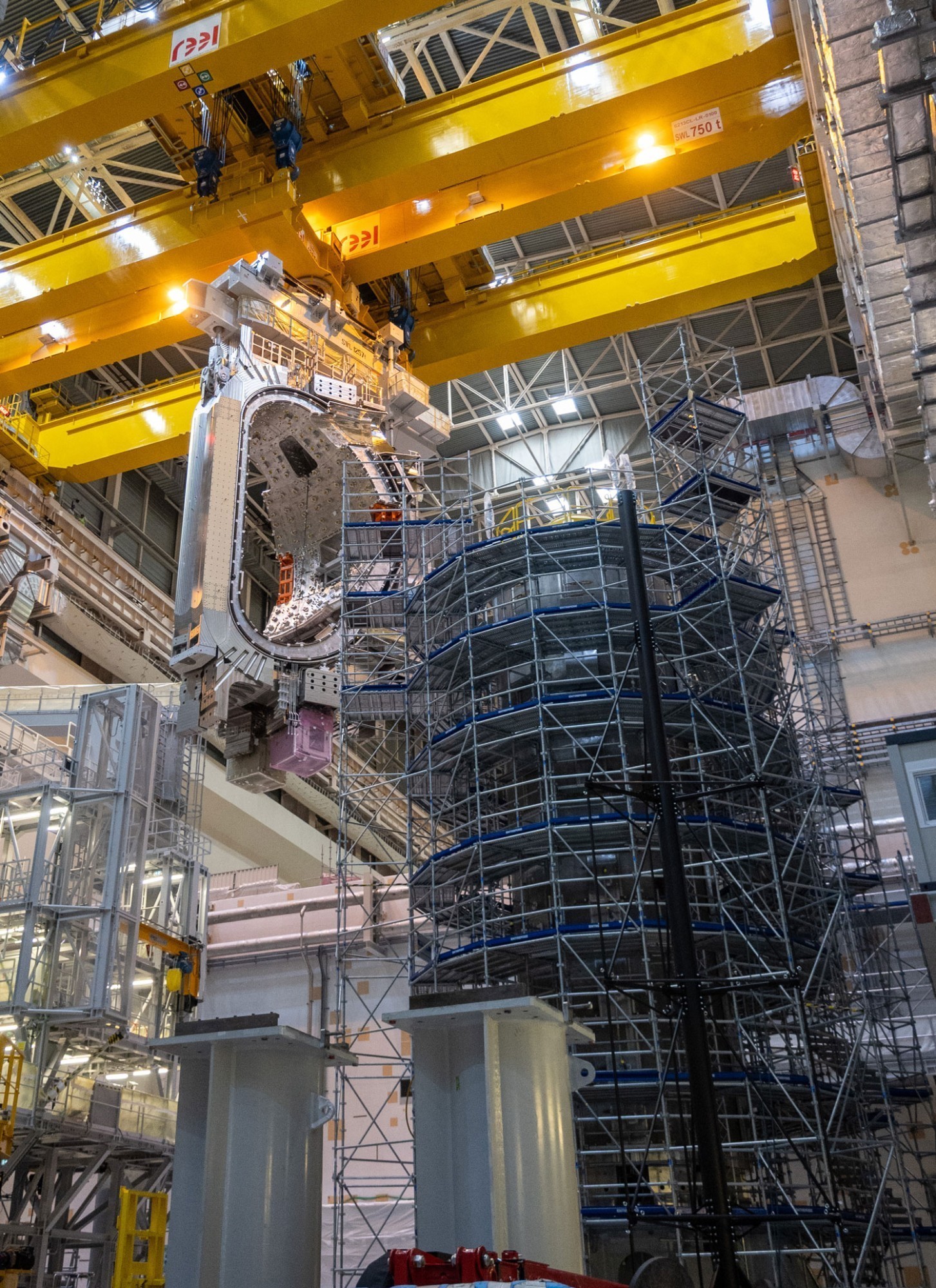 Derrière l'électroaimant central, on aperçoit le module sectoriel qui sera placé au cœur du tokamak dès que l'ensemble de la chambre à vide aura été monté et soudé.