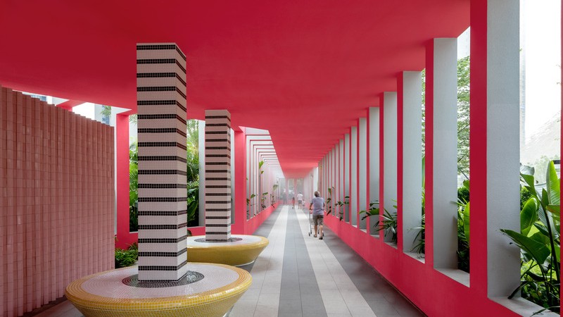 Intérieur rose vif de la colonnade paysagère des Résidences Buji, avec des colonnes à rayures noires et blanches reposant sur des bancs en mosaïque jaune, entouré de plantations luxuriantes.